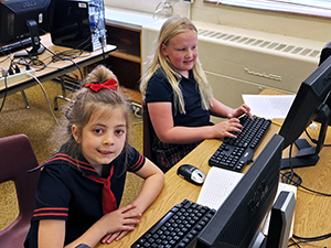 Two girls practice keyboarding in Computer Lab 1.
