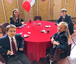 Students seated at a table ready for their Valentine's lunch.
