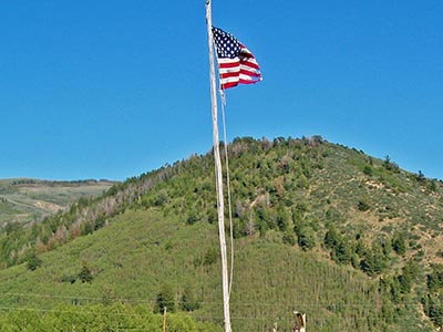 The US flag flows in a breeze in the clear blue sky.